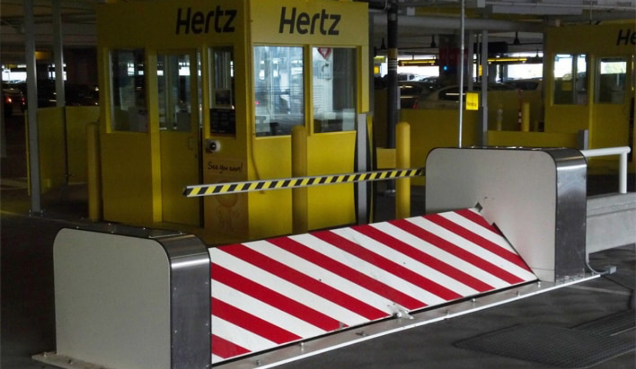 Delta Scientific security barrier deployed at a Hertz car rental facility, featuring striking yellow and black design elements that ensure high visibility, reflecting the integration of Delta's safety solutions in commercial settings for secure vehicle access.