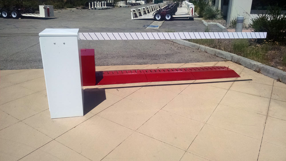 Delta Scientific surface-mounted barrier arm in a lowered position with an accompanying control pedestal, part of a comprehensive parking control gate system for secure vehicle entry points.