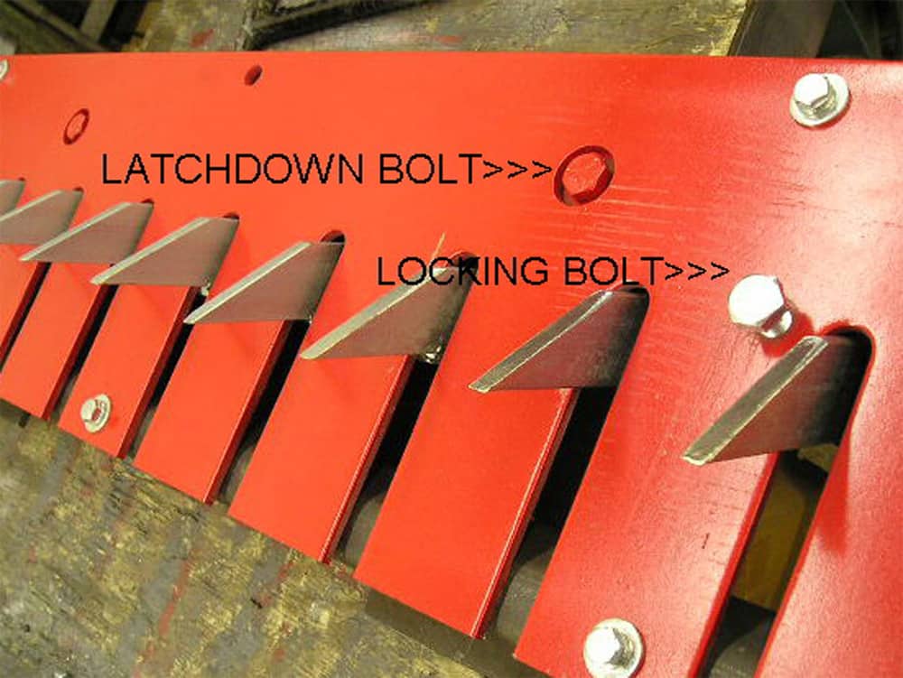 Close-up view of the sharp, red teeth of a Delta Scientific Sabre Tooth Traffic Controller, with visible latchdown and locking bolts for secure deployment, indicating the device's reliability and durability in traffic regulation and vehicle control.
