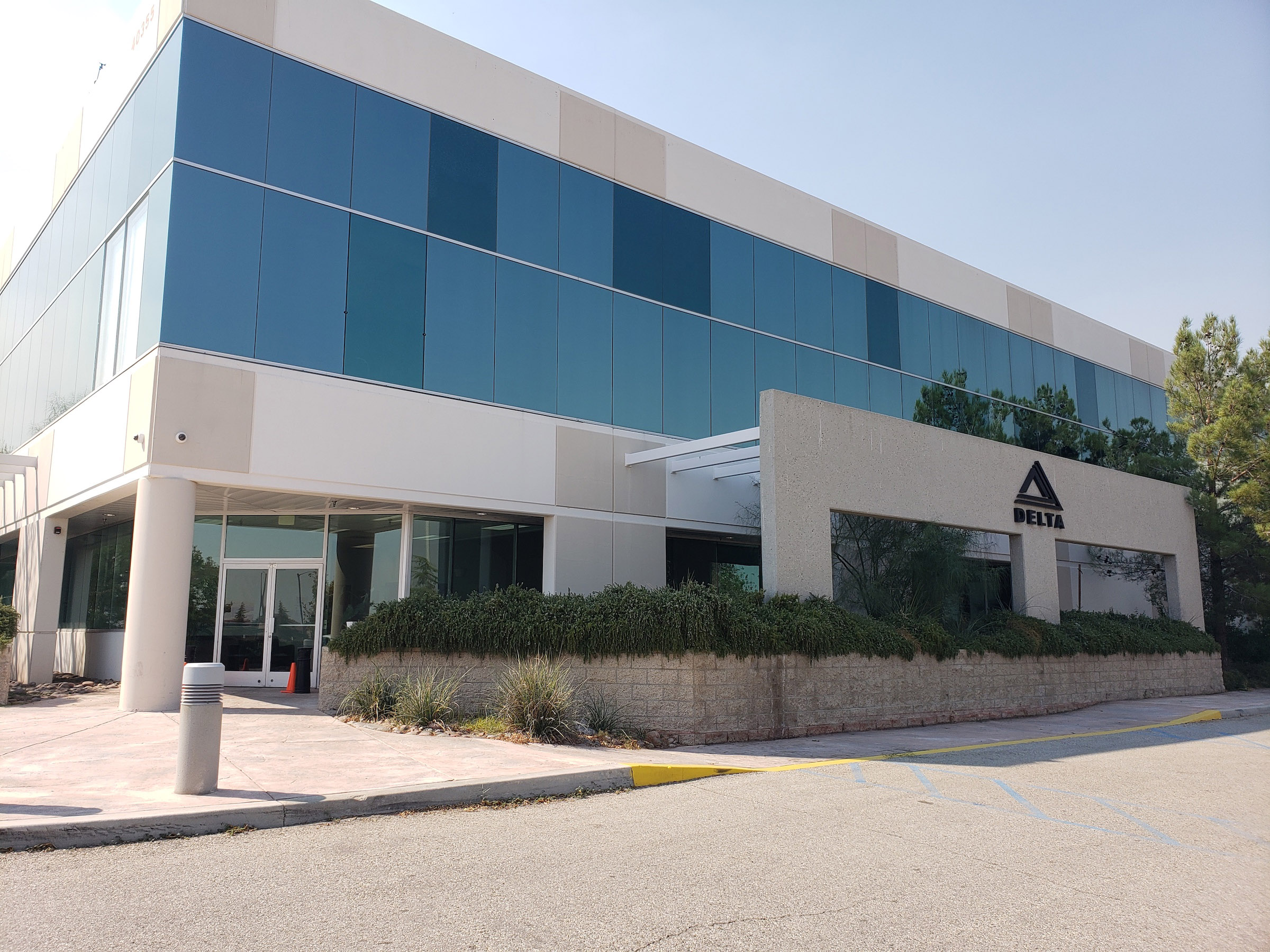 Modern corporate office building of Delta Scientific with a large company logo on the façade, showcasing the headquarters where the innovation in security and defense solutions takes place.