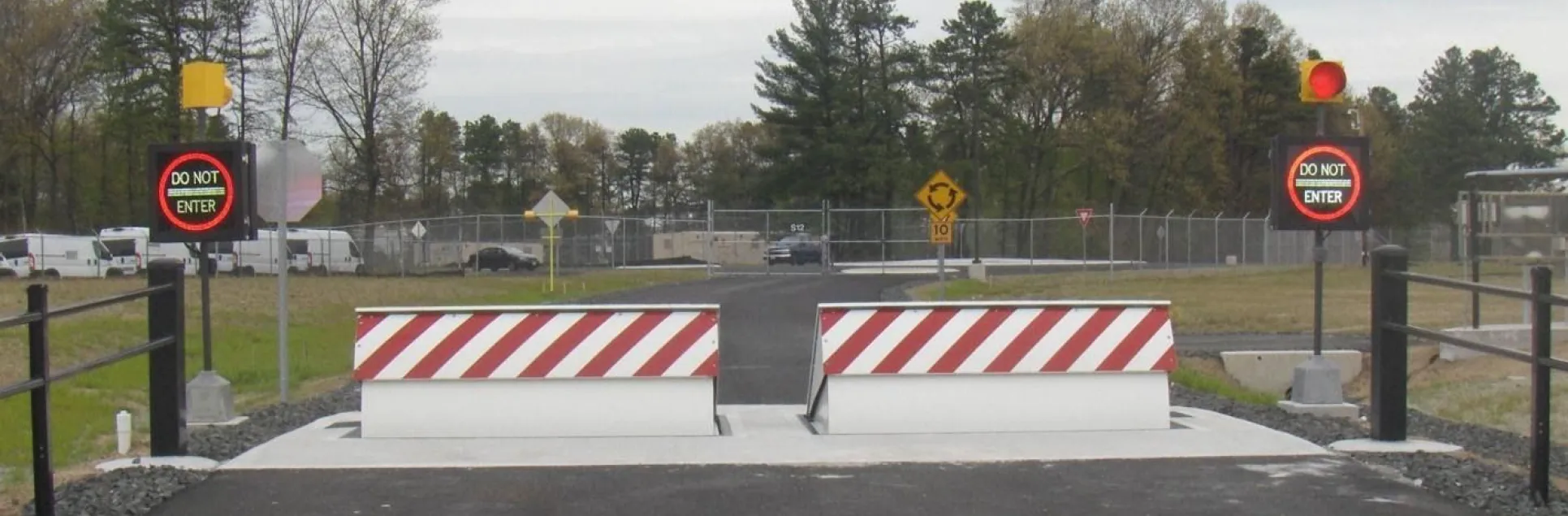 Delta Scientific's red and white striped wedge barriers with 'Do Not Enter' signs and red traffic lights, securing a government federal building's perimeter against unauthorized vehicle access.