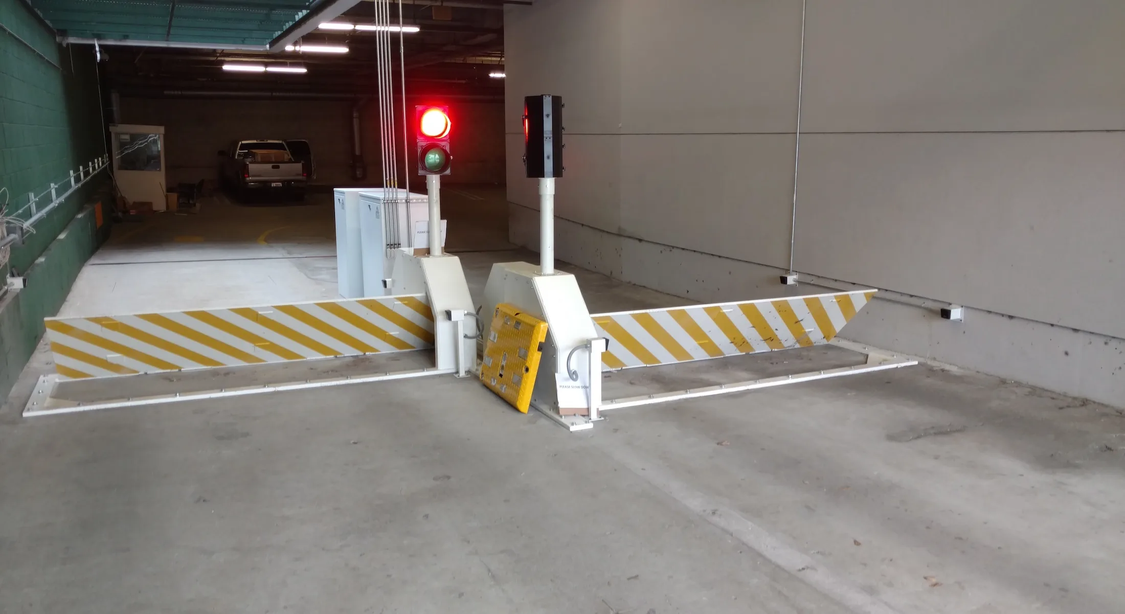 Delta Scientific's parking control barrier system deployed in an underground parking structure, complete with traffic light signals and striped barrier arms, facilitating secure vehicle access and traffic flow management.
