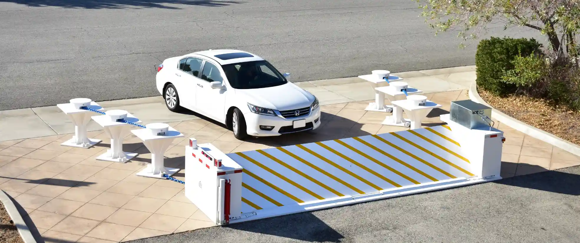 White sedan approaching a Delta Scientific high-security vehicle access control barrier with a deployed arm, showcasing the company's commitment to protecting sensitive areas through advanced engineering and design.