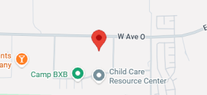 A section of a map showing a red location pin on W Ave O, near Camp BXB and the Child Care Resource Center.