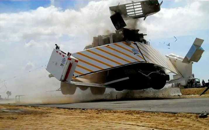 A mine-clearing vehicle detonating a mine, causing the front assembly to lift into the air as it clears temporary perimeters.